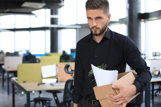 Sad dismissed worker is taking his office supplies with him from office