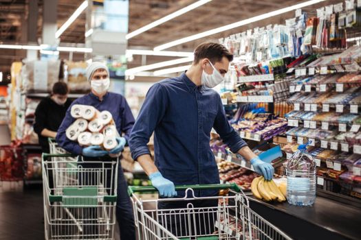 group of shoppers in protective masks standing near the checkout in a supermarket