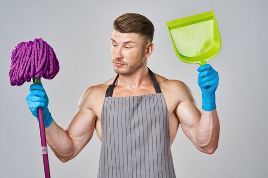 Muscled man in apron with mop posing cleaning