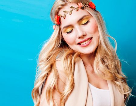 young blond woman dressed like ancient greek godess, beautiful girl hands manicured red nails on blue background copyspace