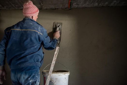 Worker plastering the wall by concrete
