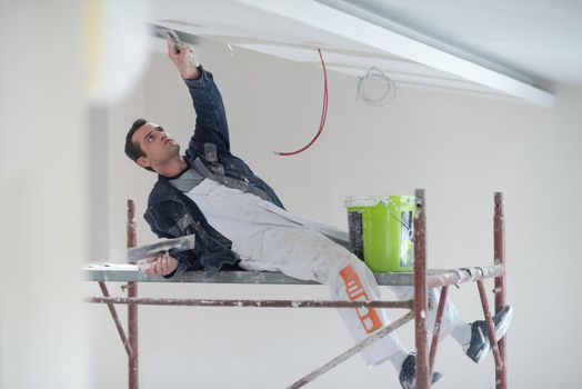 construction worker plastering on gypsum ceiling