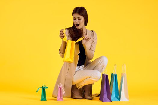 pretty woman with packages in hands Shopaholic yellow background