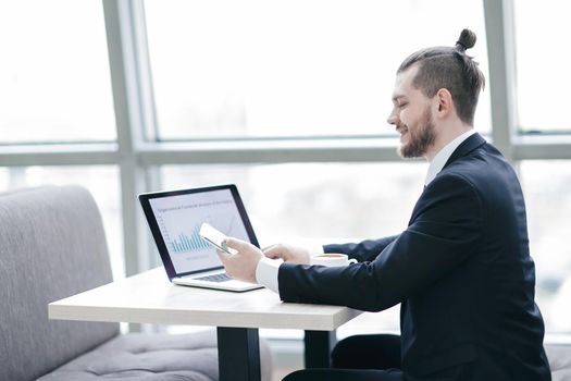 casual businessman working with mobile and laptop in modern office