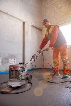 worker performing and polishing sand and cement screed floor