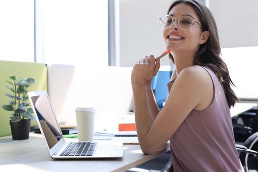 Beautiful business woman in smart casual wear working on laptop in the office