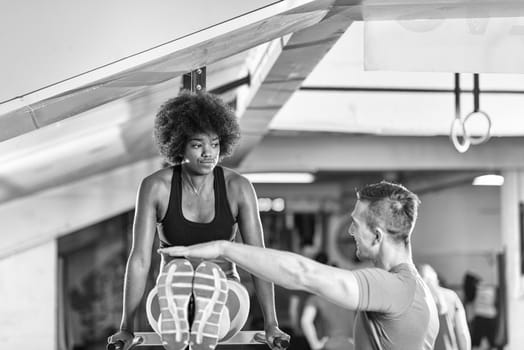 black woman doing parallel bars Exercise with trainer