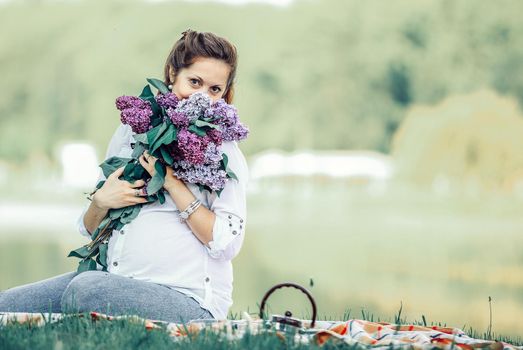 portrait of happy pregnant woman with bouquet of lilacs on a pic