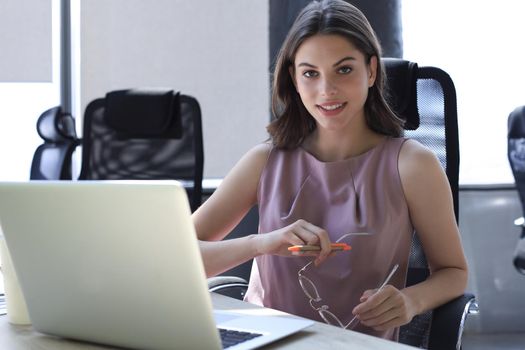 Beautiful business woman in smart casual wear working on laptop in the office