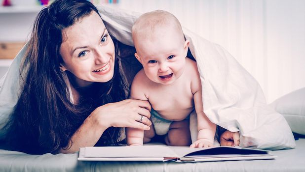 happy mother reading a book to her one year old child