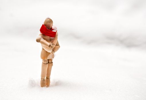 Small wooden puppet in snowdrift