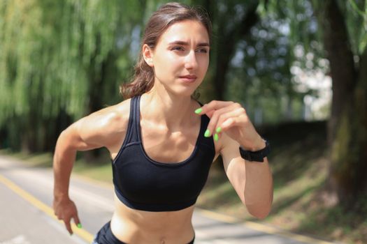 Young woman in sports clothing running while exercising outdoors.