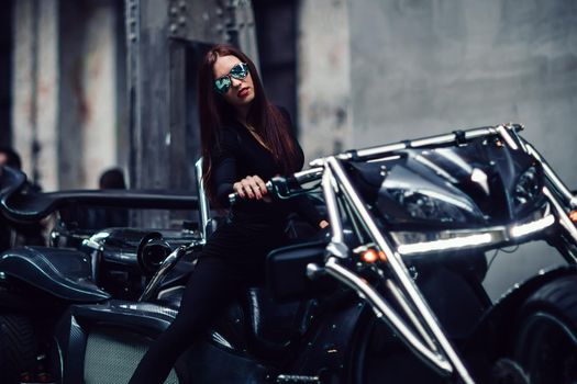 young woman in sunglasses posing sitting on a custom motorcycle