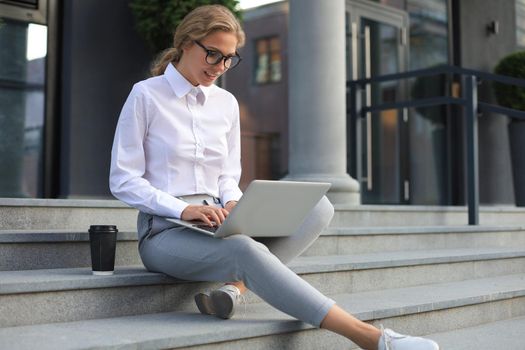 Beautiful business woman sitting near business center and using laptop.