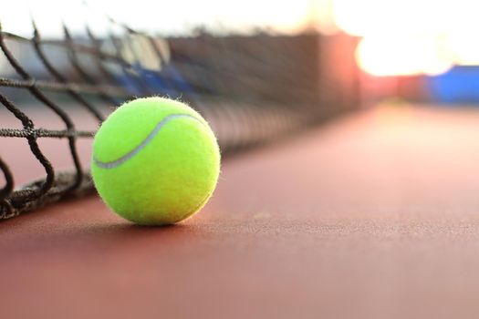 Bright greenish yellow tennis ball on clay court.