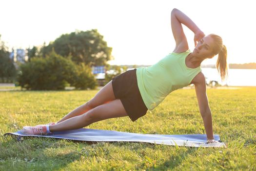 Athletic woman doing plank exercise outdoor. Work out concept.
