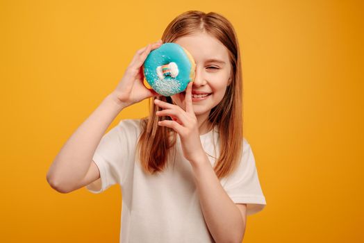 Girl with donut isolated on yellow background