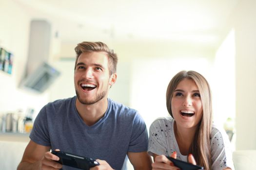 Young couple having fun playing videogame at home