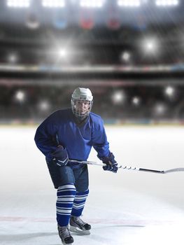 ice hockey player in action kicking with stick in front of big modern hockey arena with lights and flares
