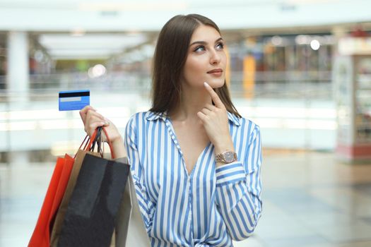 Shopper girl holding credit card and shopping bags looking up.