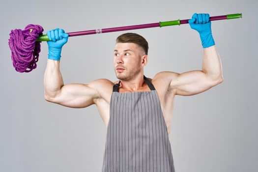 man in apron with mop in hand posing housework