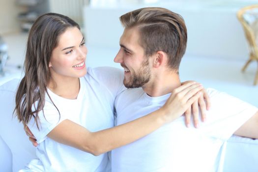Happy young couple hugging and looking at each other at home interior.