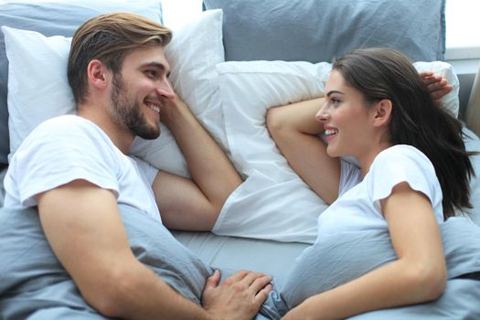 Cheerful couple awaking and looking at each other in bed.