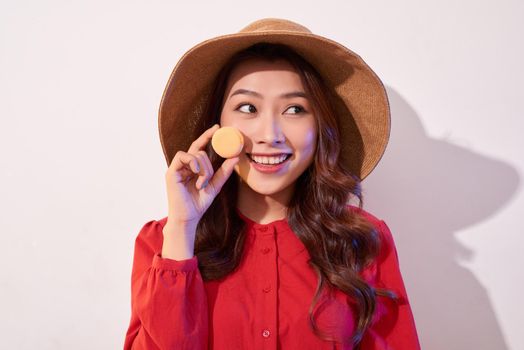 Young woman standing with french sweet cookie macaron over white background
