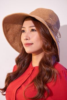 Blissful lady with broad smile posing in sunny day. Laughing girl in red clothes and trendy straw hat enjoying good weather in weekend.