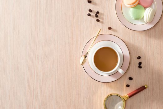Cup of coffee with macaroons and coffee beans on wooden background