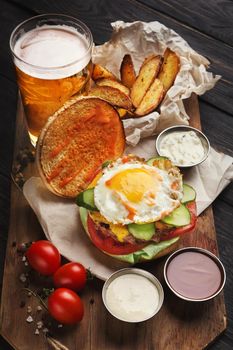 Hamburger with bacon and egg on wooden platter