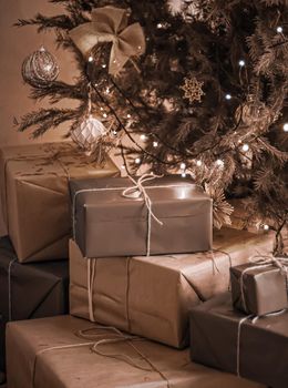 Christmas holiday delivery and sustainable gifts concept. Brown gift boxes wrapped in eco-friendly packaging with recycled paper under decorated xmas tree