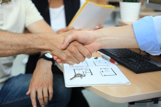 Estate agent shaking hands with his customer after contract signature.