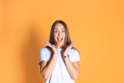 Young woman in casual clothing wondering and screaming isolated over yellow background.