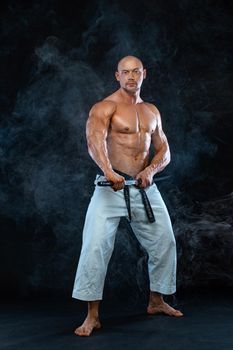 Karate fighter on black background with smoke. Shirtless man samurai with Japanese sword. Fit man sportsmen bodybuilder physique and athlete.