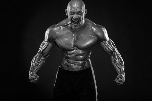 Bodybuilding competitions on the scene. Handsome and fit man sportsmen bodybuilder physique and athlete. Men's fitness motivation. Black and white photo.