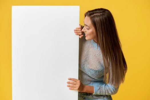 Smiling girl looking at white poster