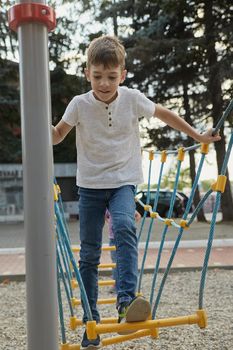boy having fun outdoors. little skinny caucasian kid playing at playground