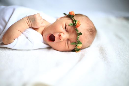 serene newborn baby on a bed yawning