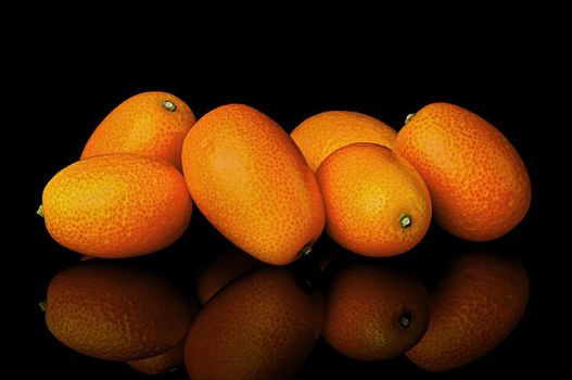Heap of ripe kumquats on black background