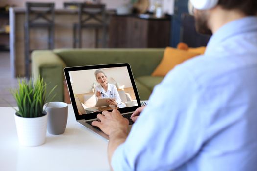 Man making video call with her doctor during self isolation and quarantine. Online consultation. Patient in video conferencing with general practitioner on digital laptop. Coronavirus.
