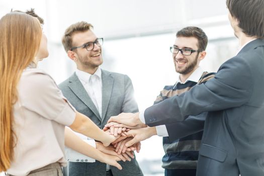concept of success in business: friendly business team standing in a circle and joining his hands together
