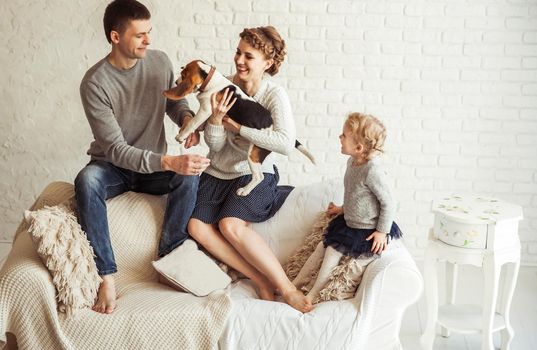 portrait of happy family with pet dog on sofa in living room