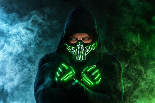 Mysterious man in black wear, neon mask and gloves. Character pastor or wizard in robe from the future. Assassin with strong face expression. Fantasy book or computer game cover concept.