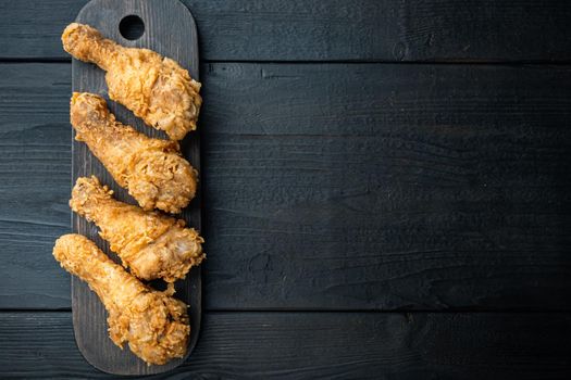 Crispy fried chicken leg on black wooden table, top view, with copy space