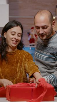 Man and woman wrapping red paper on present for christmas