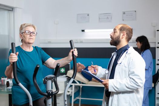 Old patient doing physical exercise with stationary bicycle