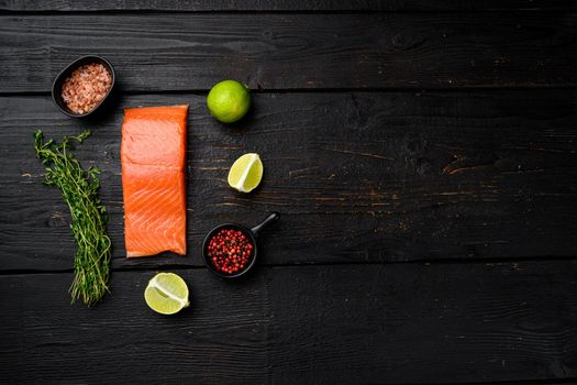 Raw Fillet of salmon, with herbs, on black wooden table background, top view flat lay, with copy space for text