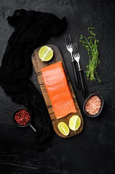 Fillet of salmon or trout, with herbs, on black dark stone table background, top view flat lay, with copy space for text