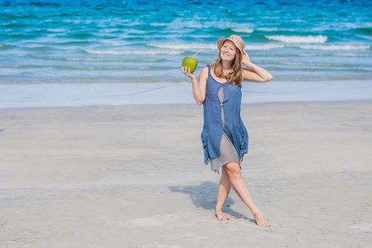 Attractive young woman drinking coconut water on the beach